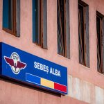 A blue sign for sebeș alba on a pink building.