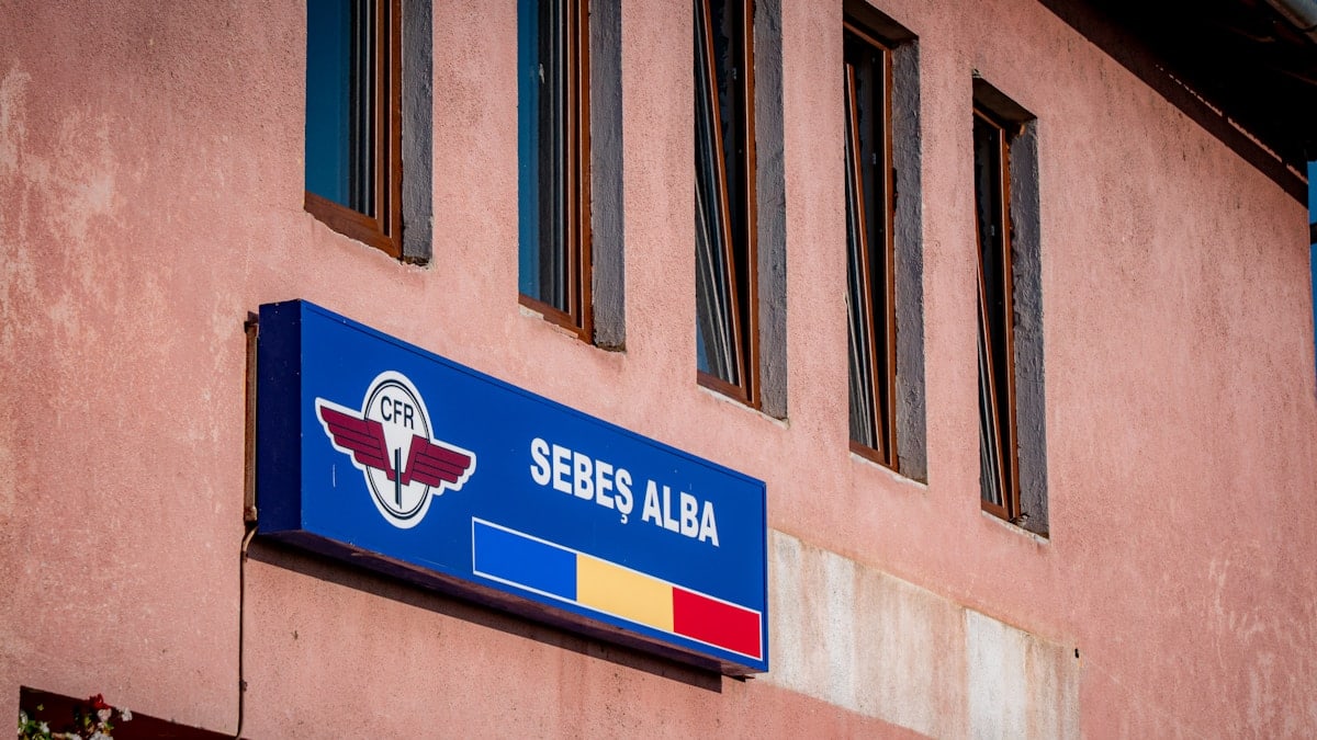 A blue sign for sebeș alba on a pink building.